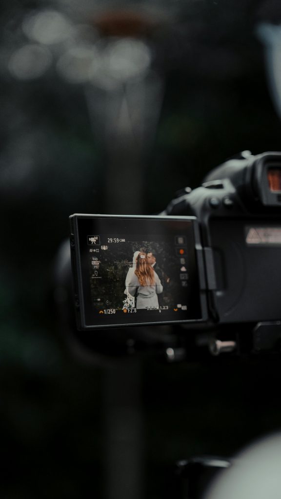 pexels-photo-11277389-11277389 Close-up of camera screen showing a couple during wedding photography outdoors.